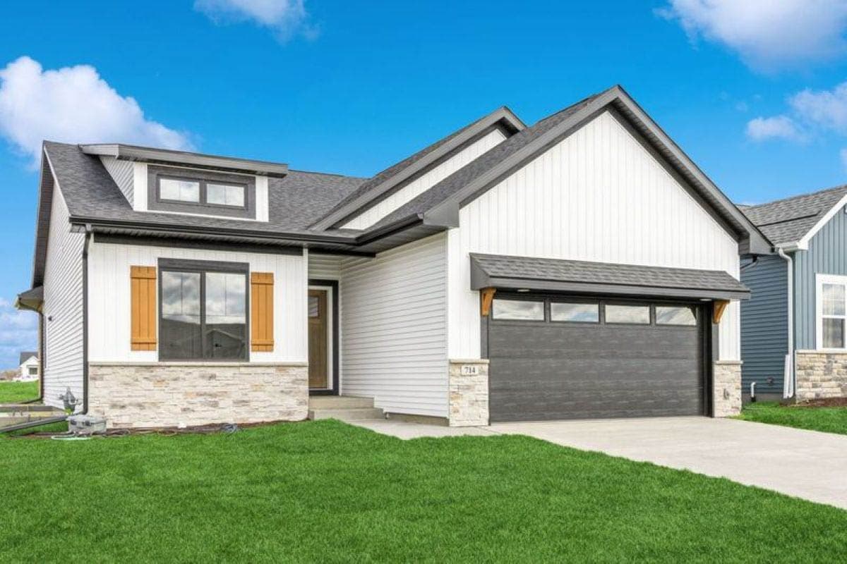 Modern house plan exterior with white siding, stone accents, gable dormer, and dark garage door.