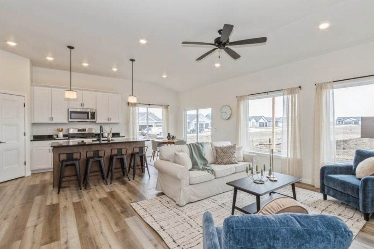 Open-concept living area with kitchen island, vaulted ceiling, large windows, and seating area.