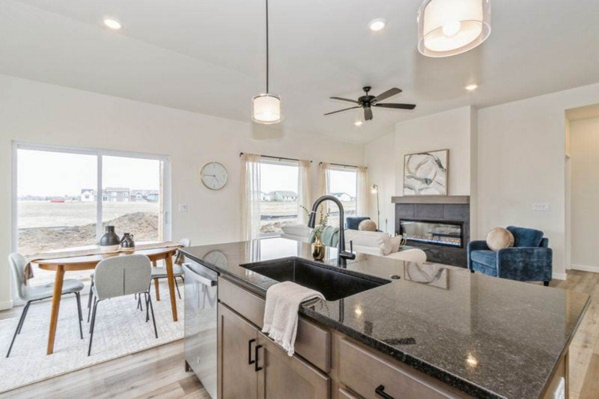 Kitchen island with sink and faucet, dining area with table and chairs, and living room with fireplace.