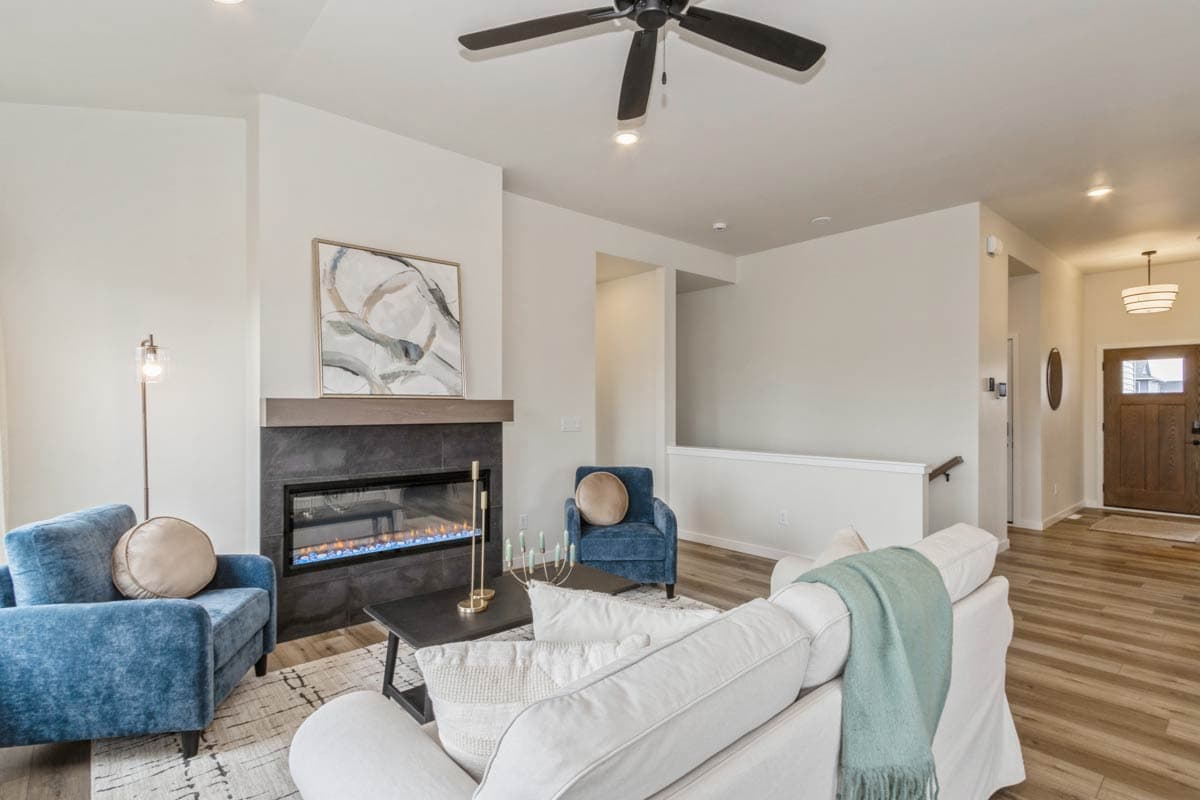 Interior view of a living room featuring a modern fireplace, sectional sofa, and entrance hallway with a wooden door.