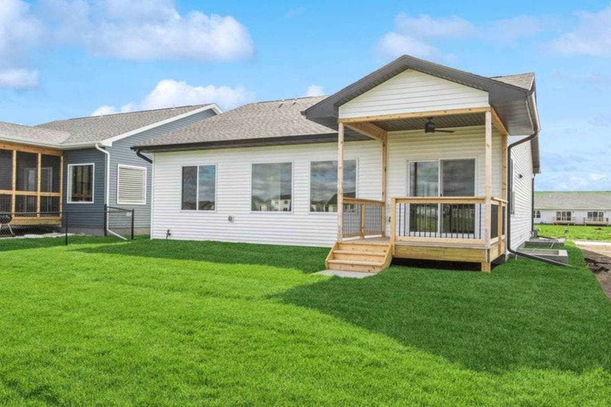 House plan exterior: Single-story modern home with vinyl siding, a covered porch with wood posts, and large windows.