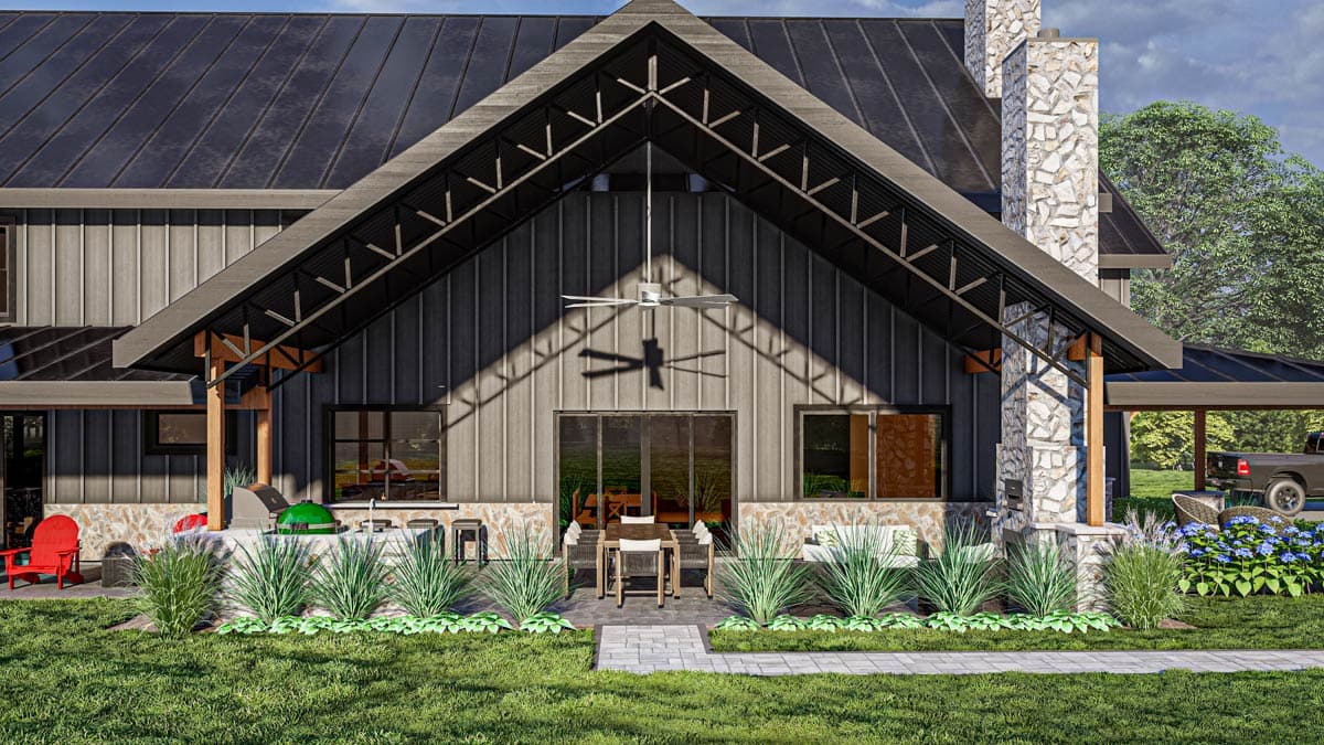Modern Farmhouse house plan exterior with metal roof, stone chimney, covered patio with outdoor kitchen and ceiling fan.