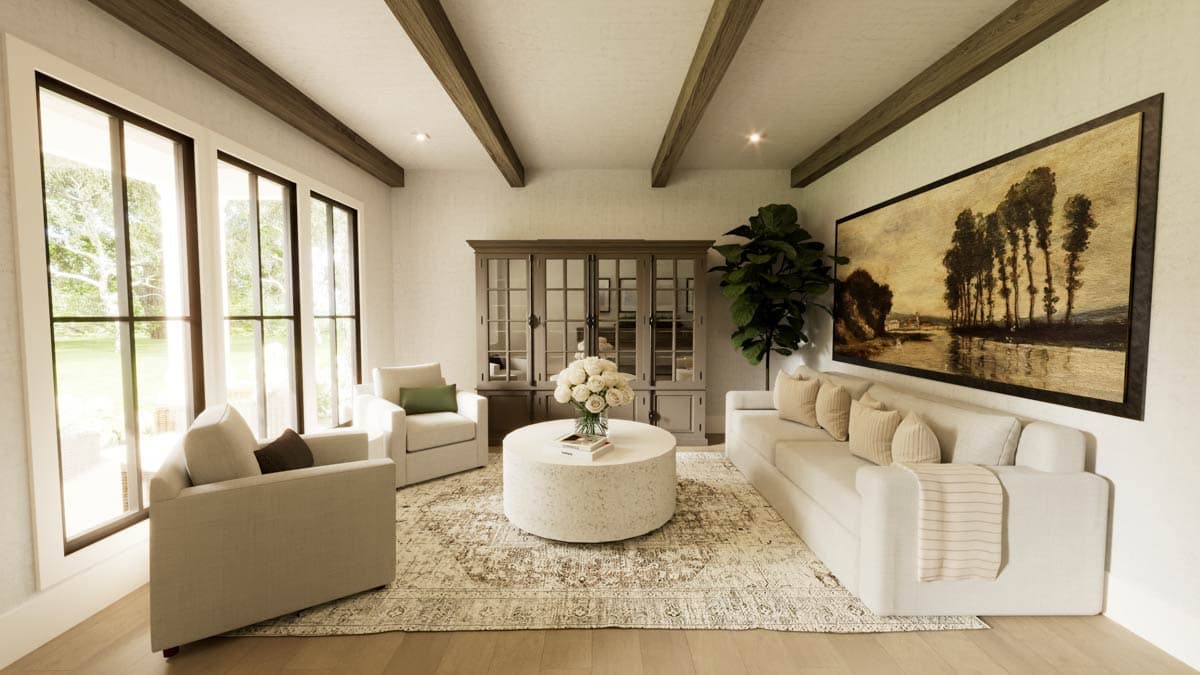 A well-lit living room with neutral colors, large windows, and a landscape painting. Features include sofa, armchairs, and a round coffee table.