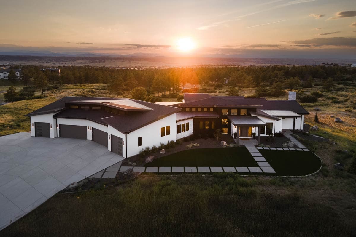 House plan exterior with modern design. Features include a three-car garage, multiple rooflines, and a covered porch. Single-story structure.