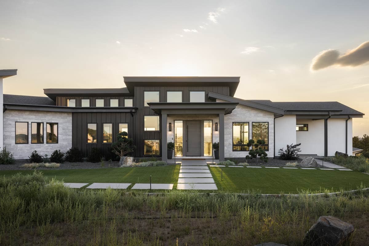 Modern house plan exterior with layered rooflines, stone and vertical siding, and expansive windows.
