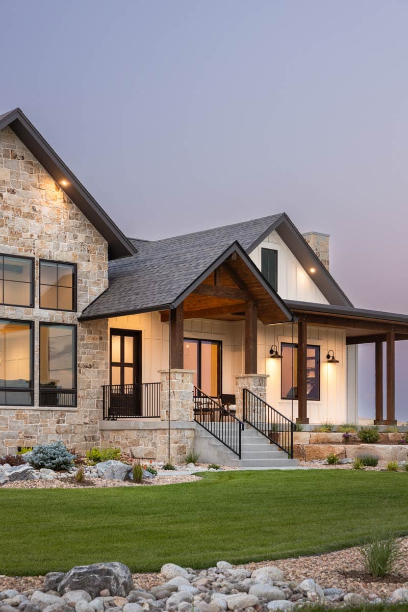 Modern Farmhouse exterior with stone accents, gabled roof, covered porch with exposed beams, and large windows.