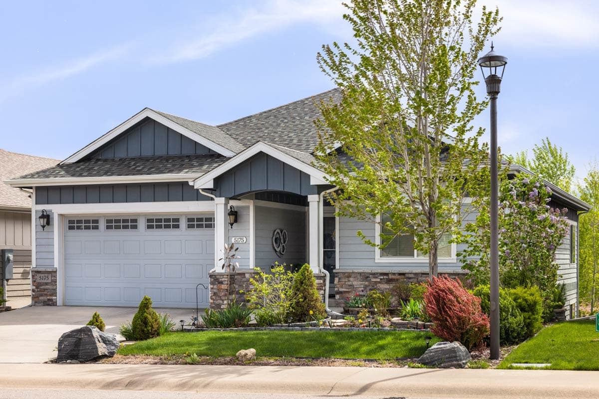 Modern Farmhouse style house plan exterior with a two-car garage, covered entry porch with stone accents, and multi-level gables.