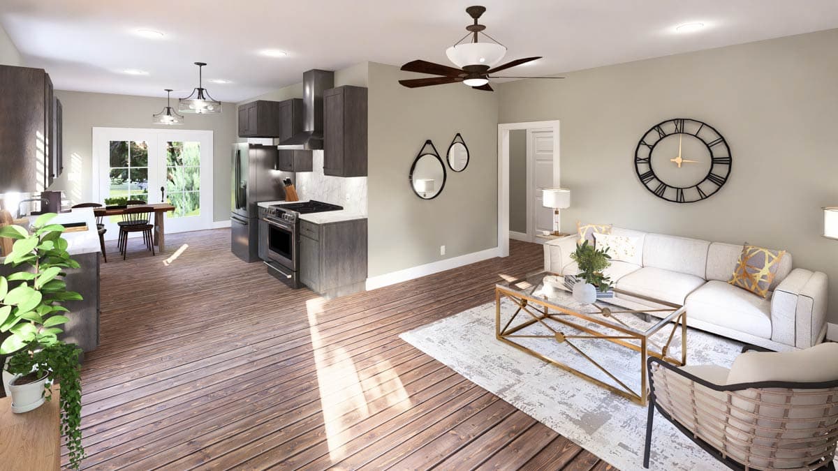 Open concept kitchen and living area with dark cabinets, stainless steel appliances, dining table, white sofa, and coffee table.