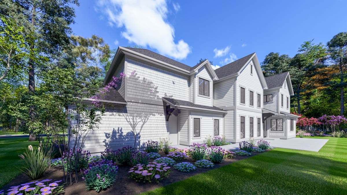 Exterior shot of a white house with a manicured garden. Lush trees surround the home under a blue sky.