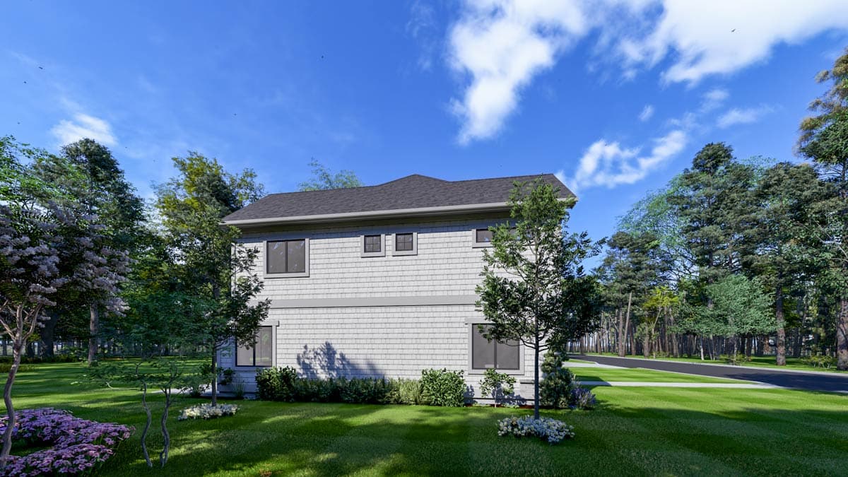 A two-story house with shingle siding, surrounded by lush green lawn and trees, under a bright blue sky with clouds.