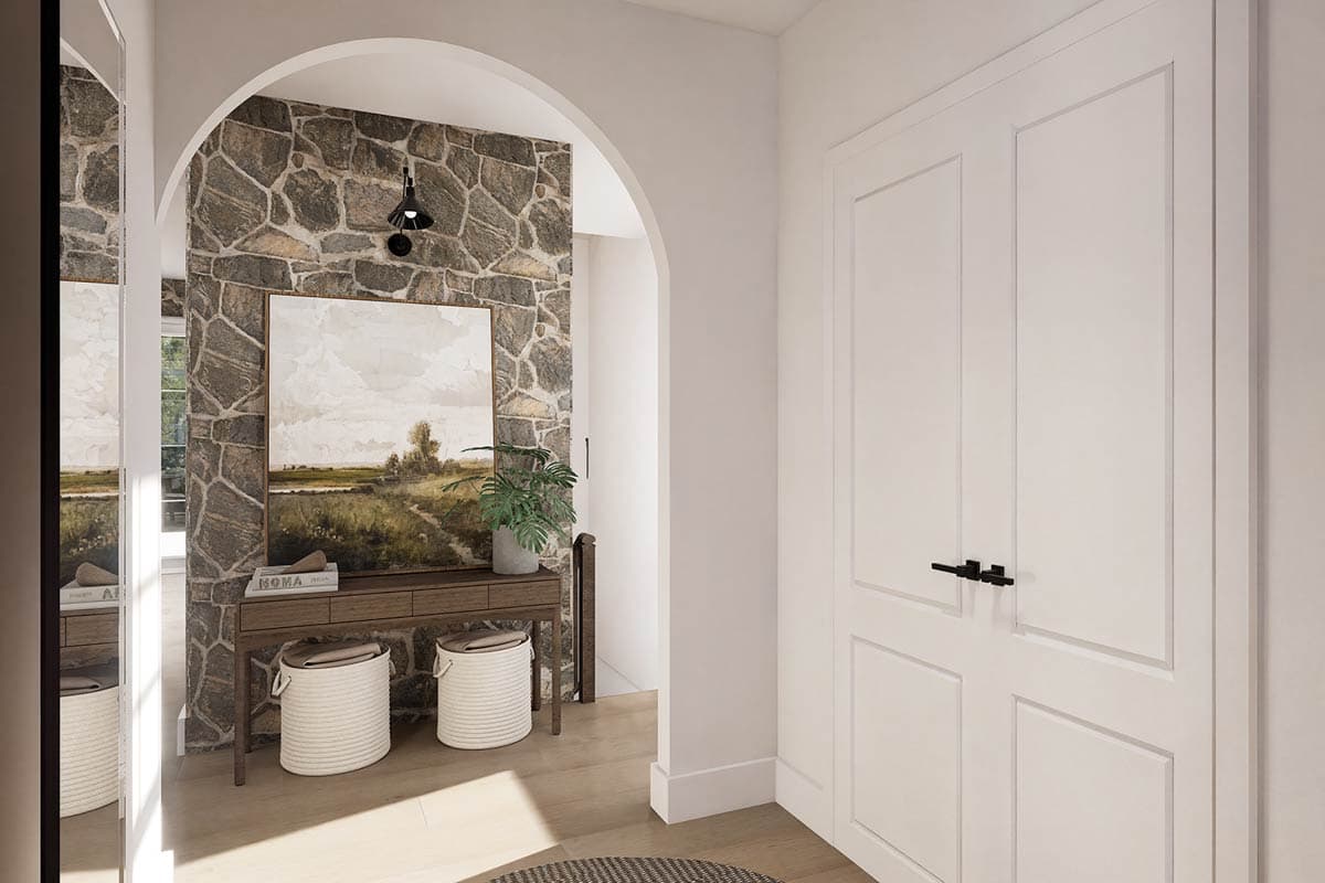 A hallway with a stone accent wall leading to a doorway, a painting, a console table with baskets, and a closed white door with a black handle.