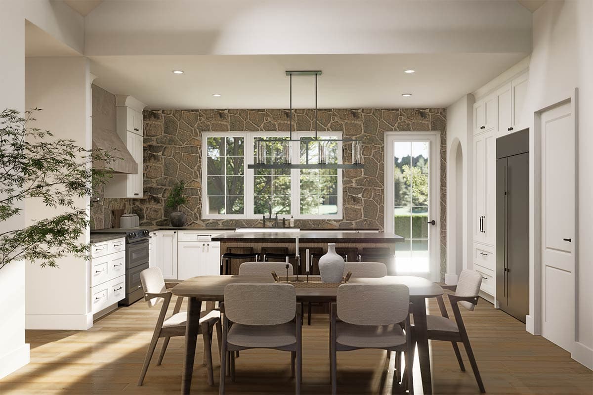 Spacious, modern kitchen with a large dining table, stone accent wall, and a large window looking out to a bright outdoor scene.
