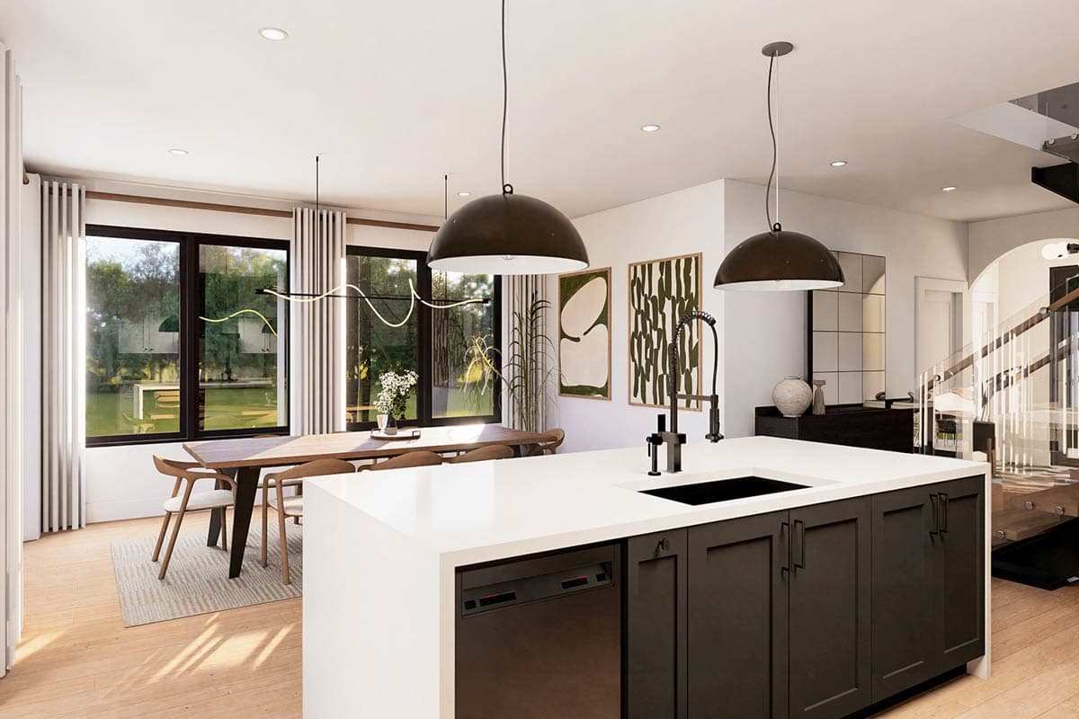 Modern kitchen with large island, contemporary pendant lights, dining area, and extensive windows overlooking a backyard.