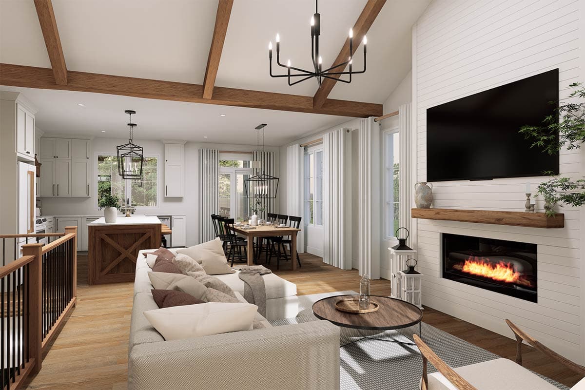 Open concept living area with kitchen island, dining table, fireplace, and vaulted ceiling with exposed beams.