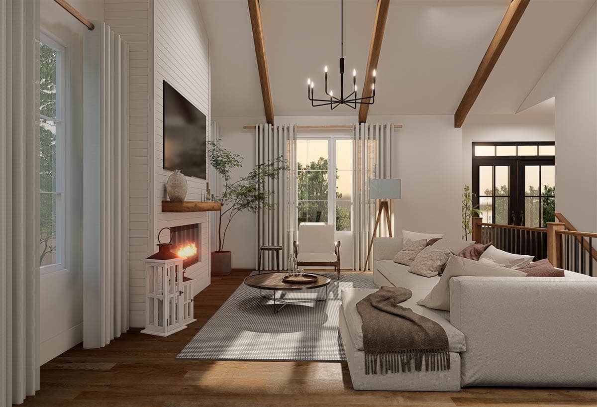 Great room with vaulted ceiling, exposed beams, fireplace, sectional sofa, and large windows.