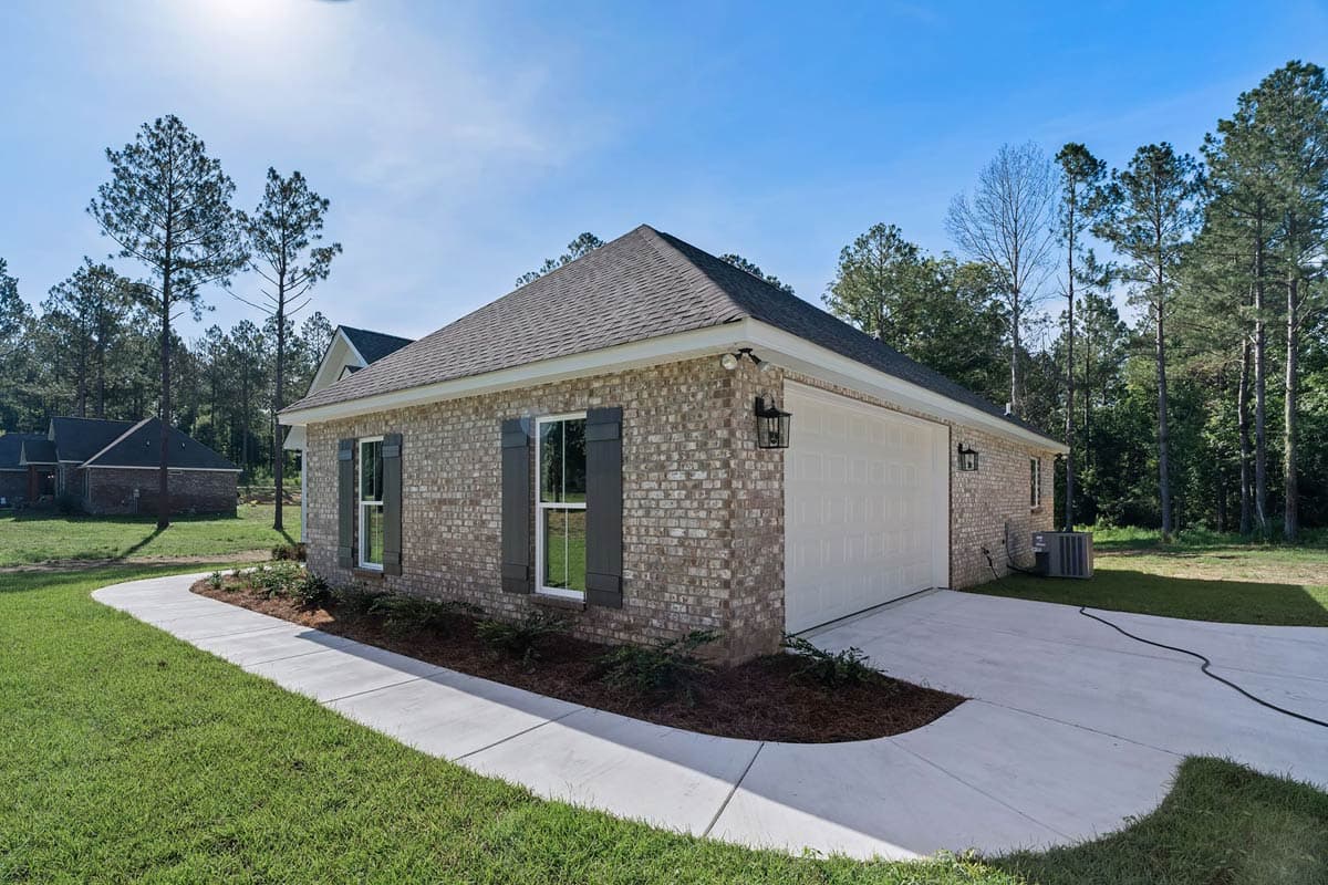 House plan exterior: One-story brick home with a side-entry garage, gable roof, and dark shutters.