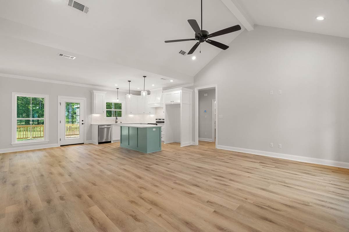 Open concept living space with vaulted ceiling, kitchen island, and access to deck.