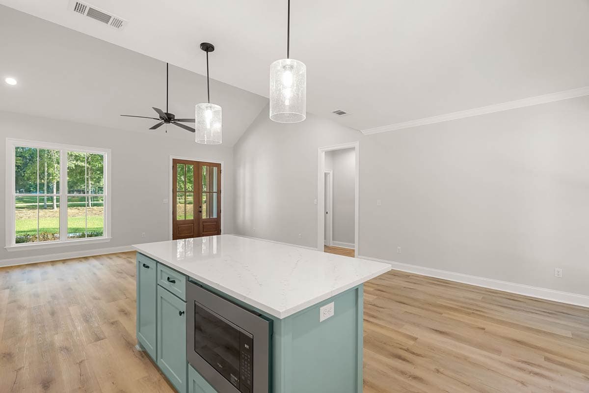 Open concept living area with vaulted ceiling, kitchen island with microwave, and double wood doors.