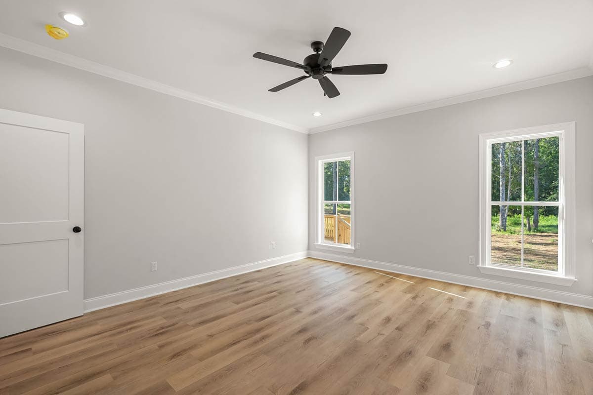 Interior view of a room with wood-look flooring, a ceiling fan, recessed lighting, a closet door, and two windows with natural light.