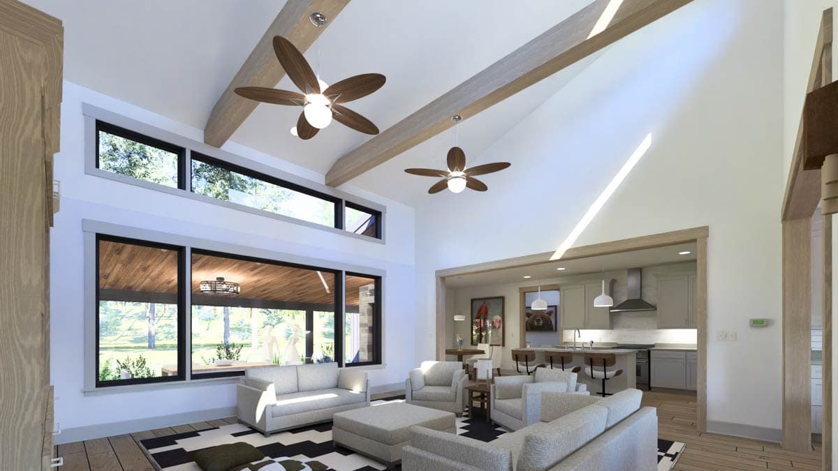 Living room with vaulted ceiling, exposed beams, ceiling fans, and large windows. Open to kitchen with island.