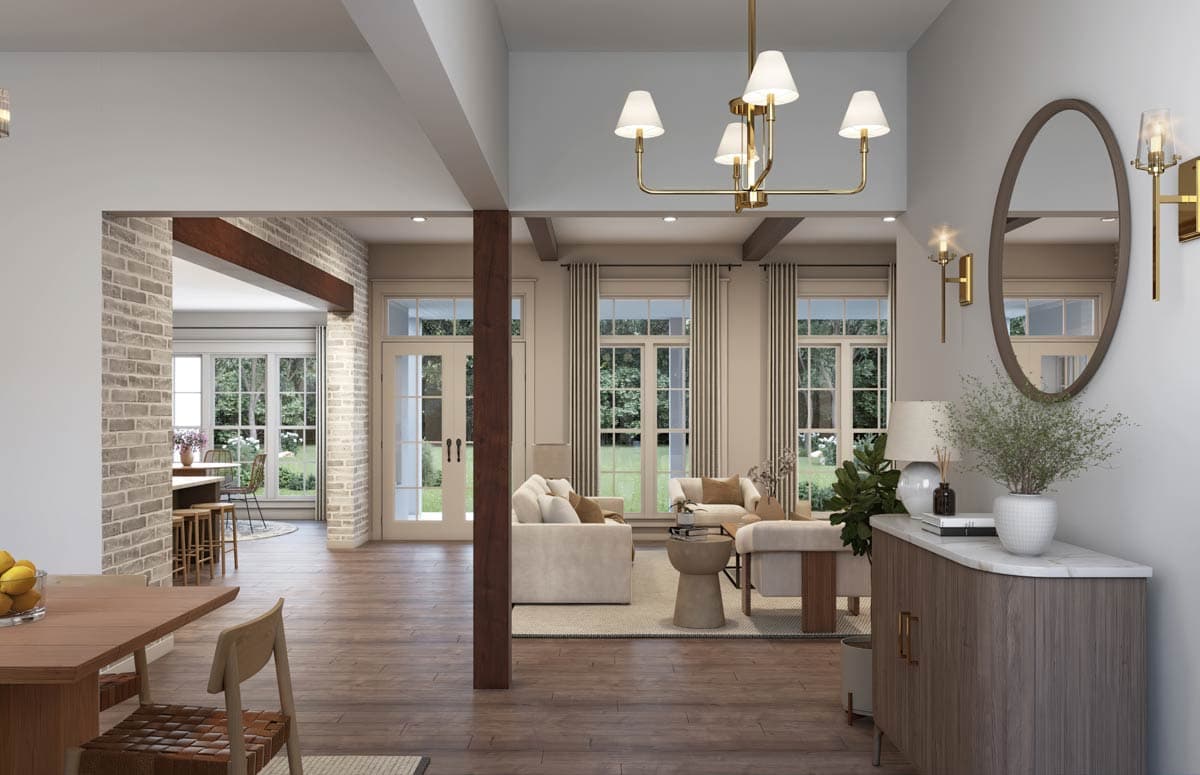 Open-concept living and dining area with exposed beams, brick accents, and large windows overlooking a garden.