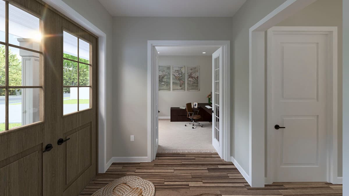 Interior view of entryway with wooden double door and view into home office with desk and maps on wall.