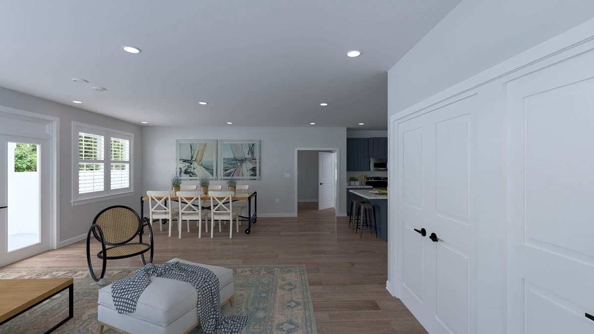 Open-concept interior rendering showing dining area with a wooden table and chairs, leading to a kitchen with dark blue cabinets and an island.