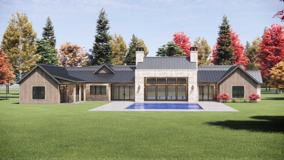 Modern farmhouse with a dark roof and stone facade. The home has a pool and is surrounded by colorful trees during the fall season.