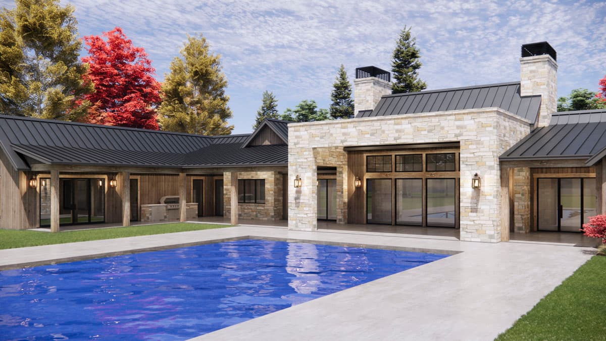 Modern luxury home with a pool, stone and wood exterior, and dark roofing. Tall trees with fall colors border the home on a sunny day.