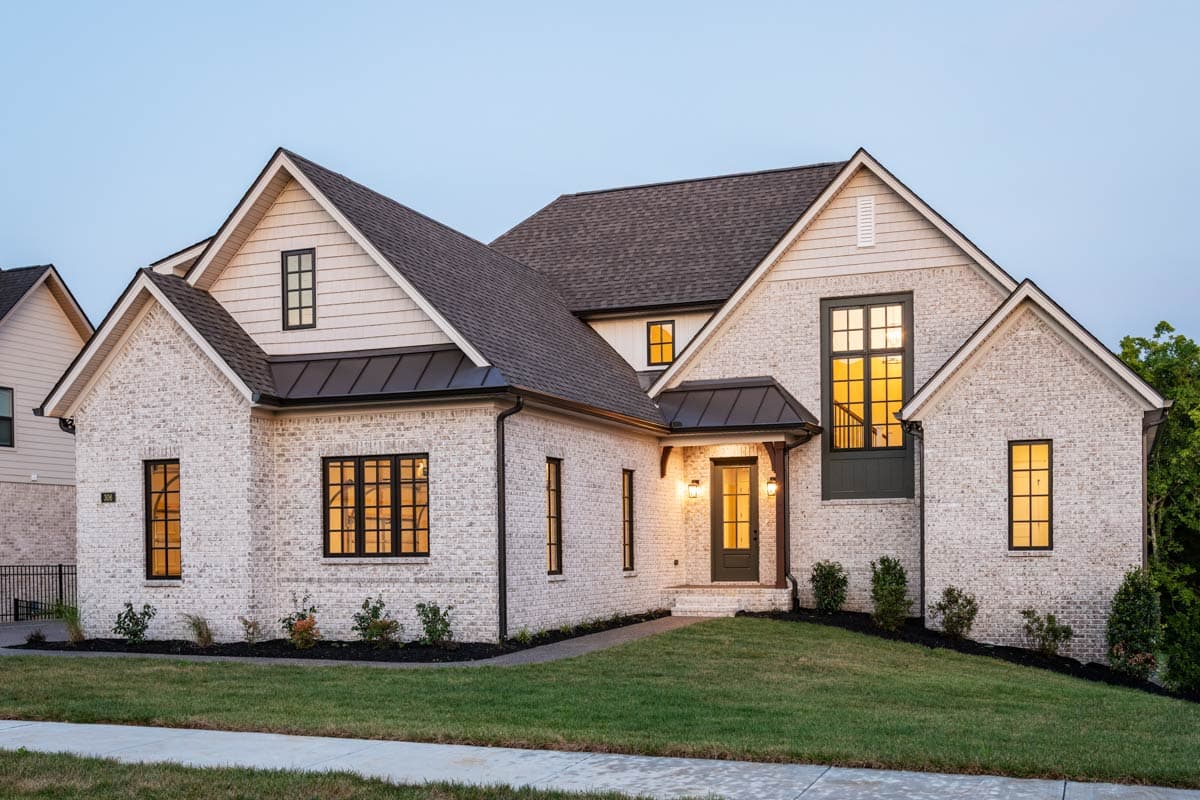 Modern Farmhouse style house plan exterior with white brick, prominent gables, dormers, and dark metal roof accents.
