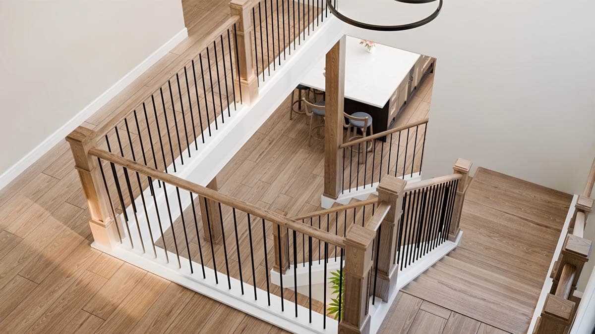 An overhead view of a staircase featuring light wooden steps and railings with black metal balusters, leading down to a kitchen area.