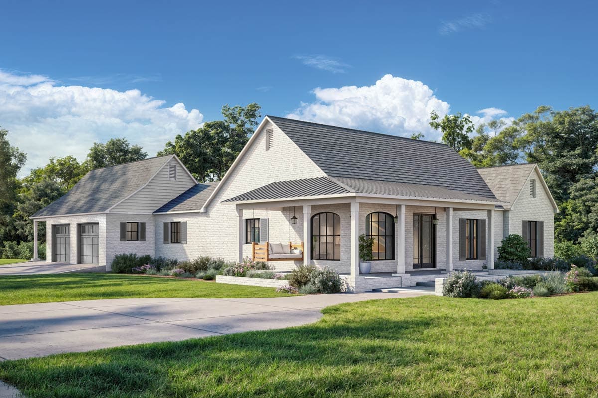 A white brick house with a porch swing sits on a green lawn, driveway leading up to it. Blue sky with fluffy clouds.