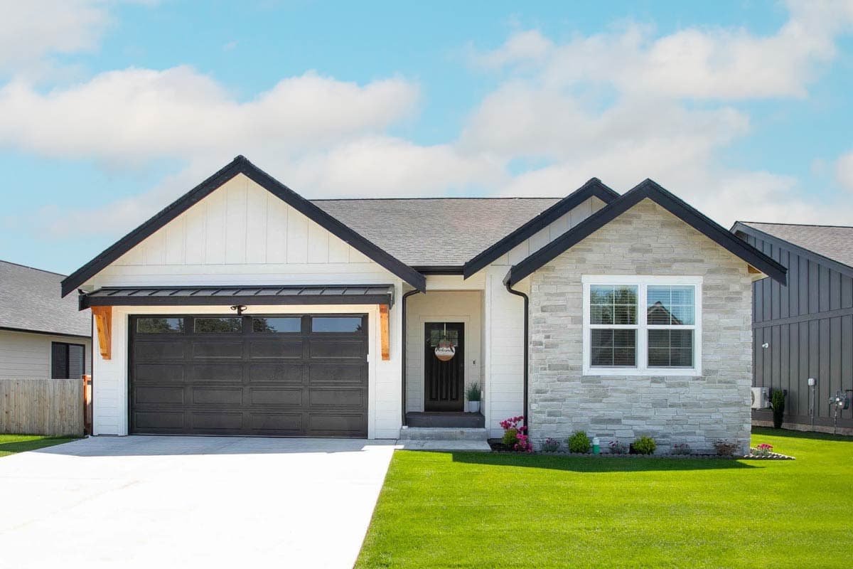 House plan exterior. Modern Farmhouse style with a single story. Features include a front-facing garage, gabled roof, and stone facade accents.