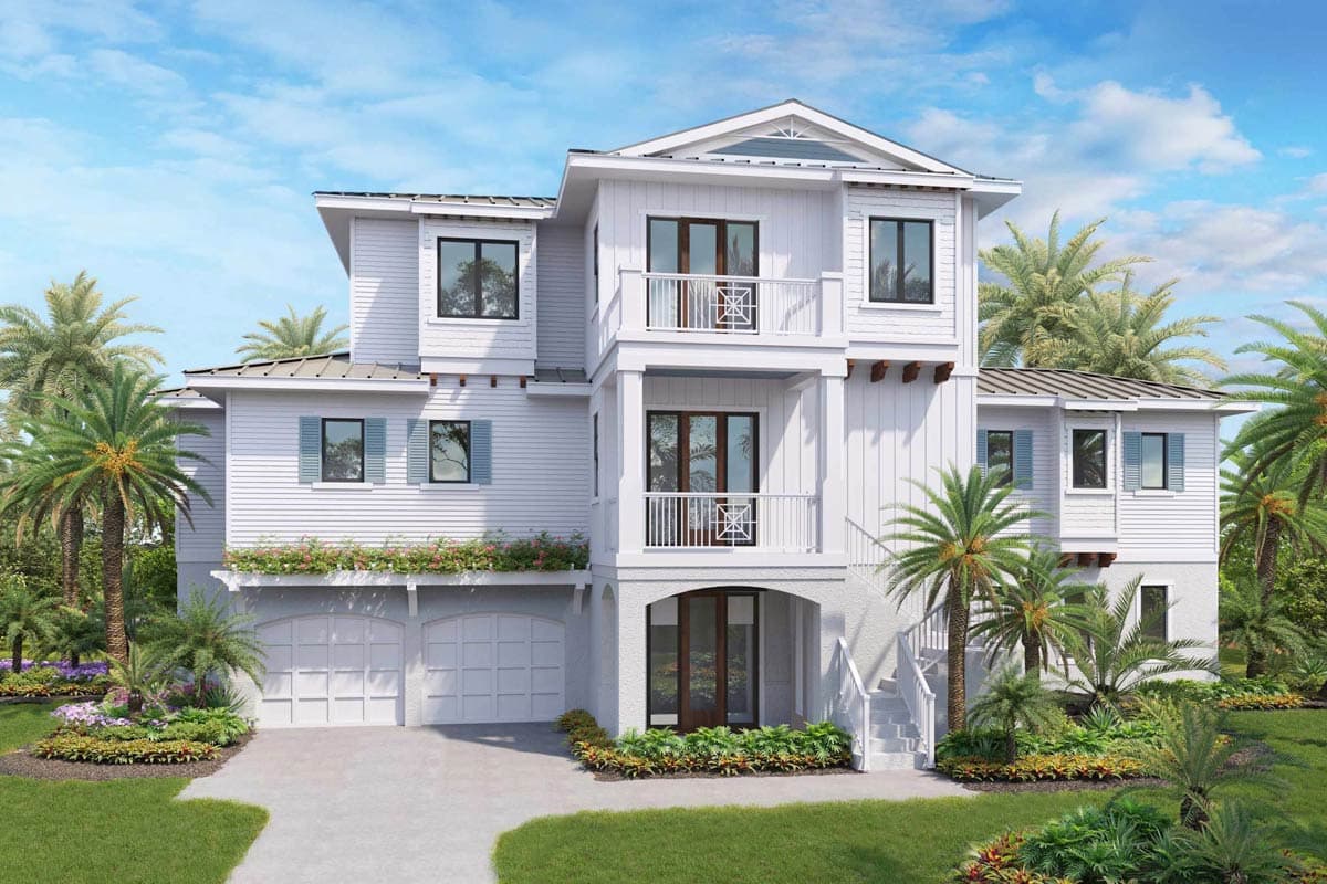 A white three-story beach house with balconies, palm trees, and a two-car garage under a bright, sunny sky. 