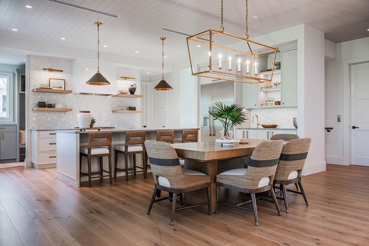 Spacious, modern kitchen and dining area. A large island with bar stools contrasts with a wooden dining table and upholstered chairs.