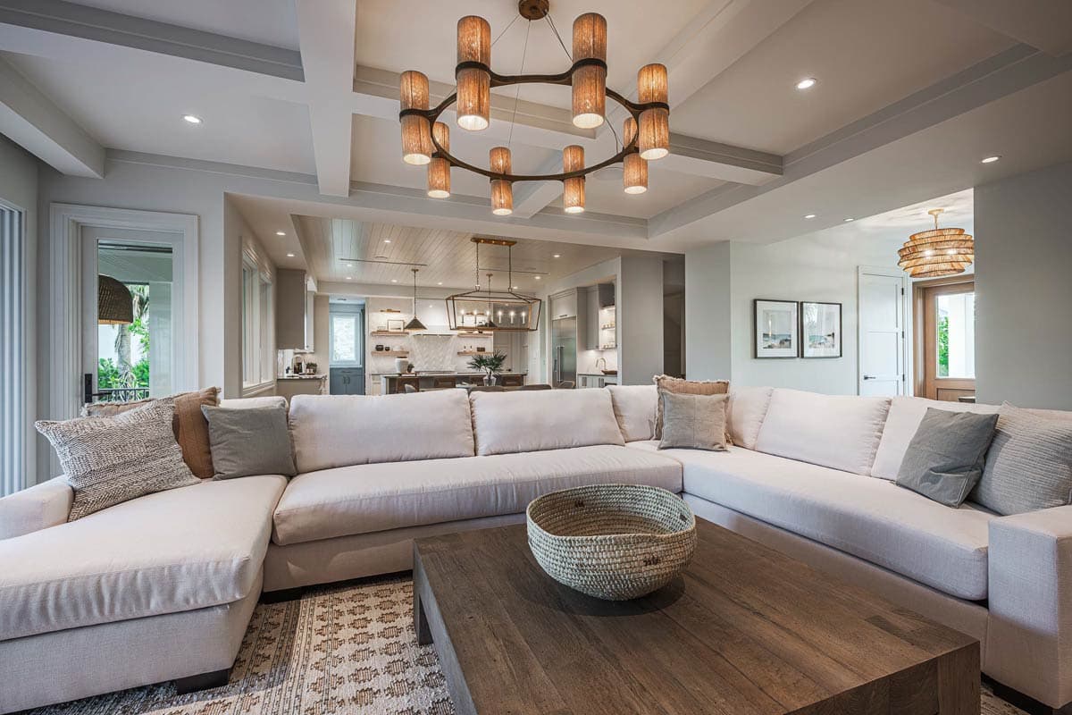A modern living room featuring a large sectional sofa, wooden coffee table, and an eye-catching circular chandelier.