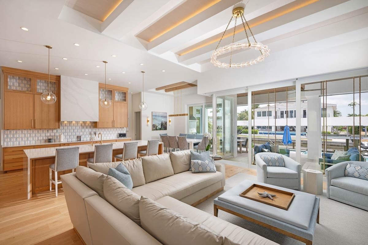 Open concept living area with kitchen island, sectional sofa, and water views through sliding glass doors.