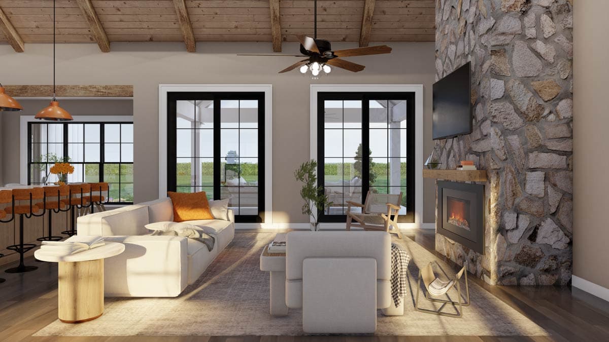 Open concept living area with vaulted wood beam ceiling, stone fireplace, and large windows.