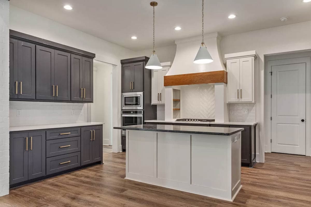 Kitchen with two-tone cabinets, island with seating, built-in microwave and oven, and a decorative range hood.