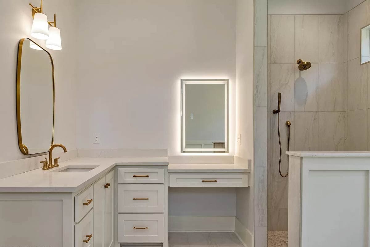 Bathroom vanity with double sinks, makeup station with backlit mirror, and tiled walk-in shower.