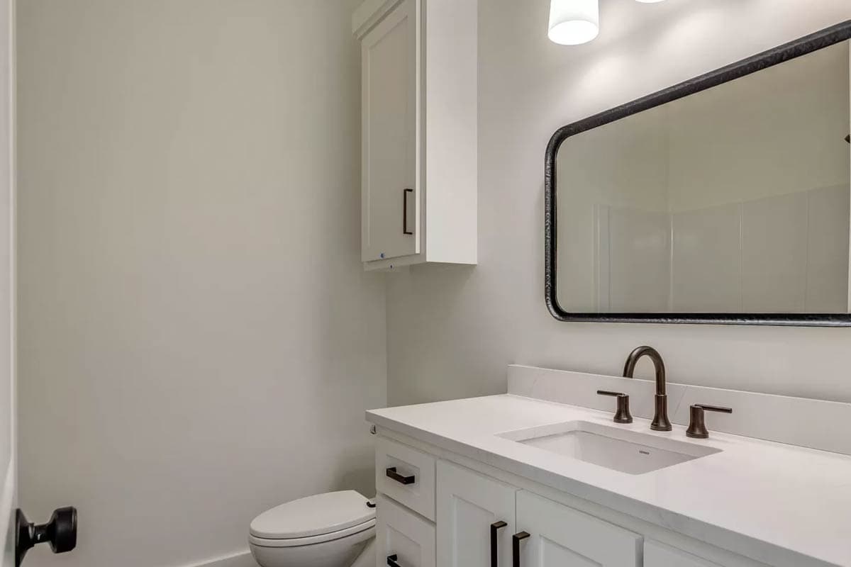 Bathroom vanity with white quartz countertop, undermount sink, modern faucet, and black framed mirror above.