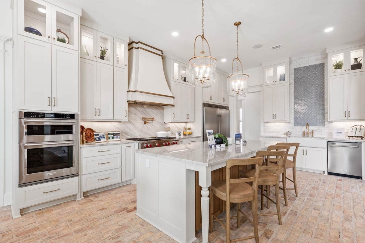Kitchen with white cabinets, a large island with seating, double ovens, and a gas range.