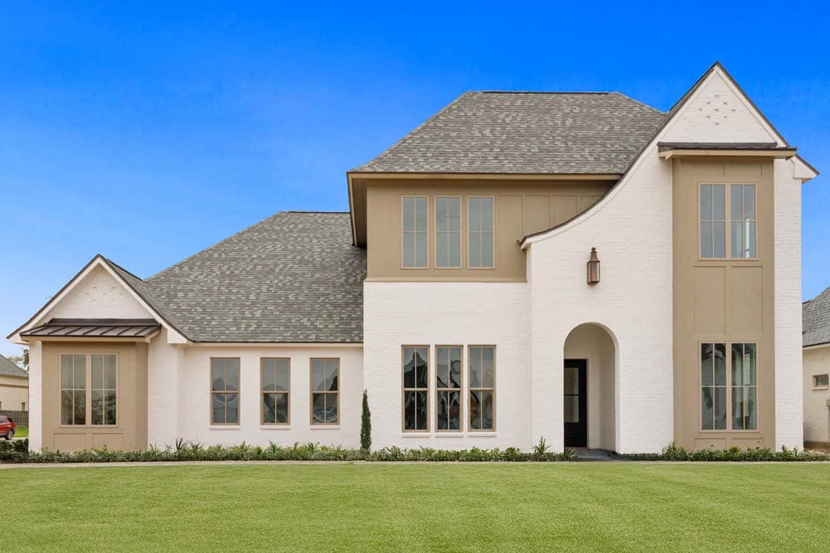 House plan exterior featuring a two-story design. Highlights include gabled rooflines, arched entry, and various window styles. White brick facade.