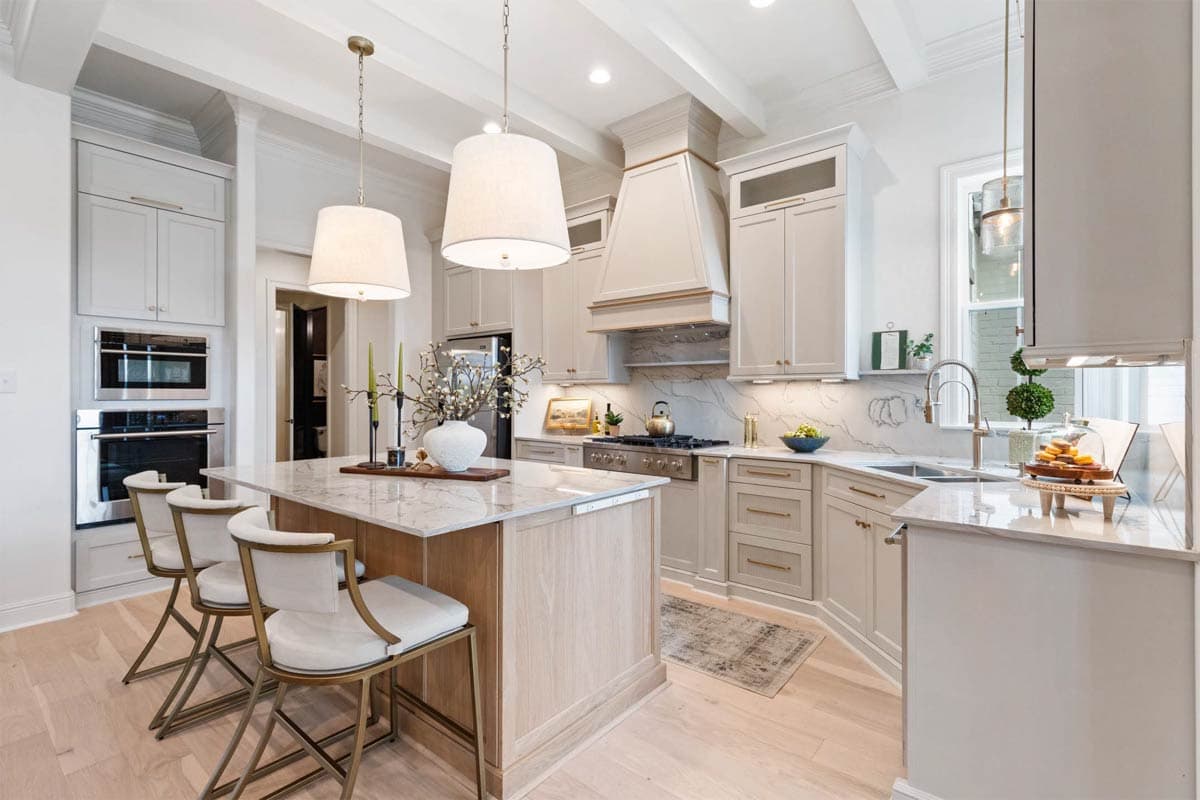 Kitchen with central island, white marble countertops, stainless steel appliances, and coffered ceiling with exposed beams.