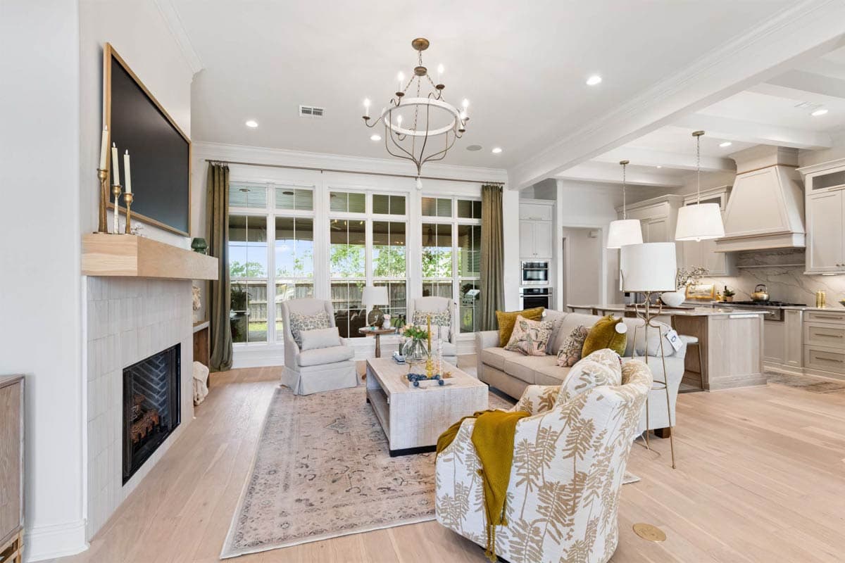 Interior rendering of open-concept living area with fireplace, large windows, and kitchen island.