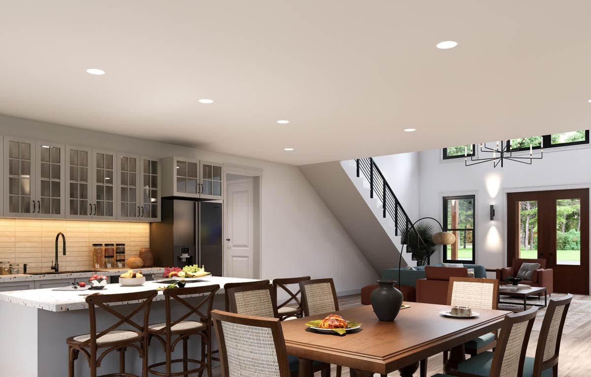 Open-concept living area with kitchen island, dining table, and living room featuring a staircase.