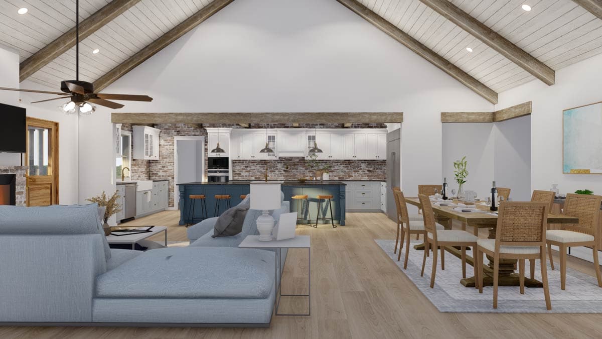 Open-concept living space with vaulted ceiling, exposed beams, kitchen island, dining area, and fireplace.