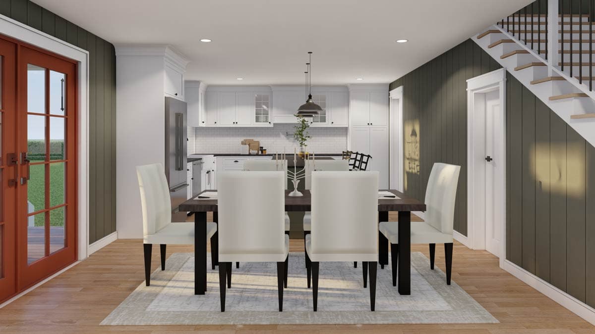 Dining area adjacent to kitchen with white cabinets, island, and staircase. Doors lead outside.