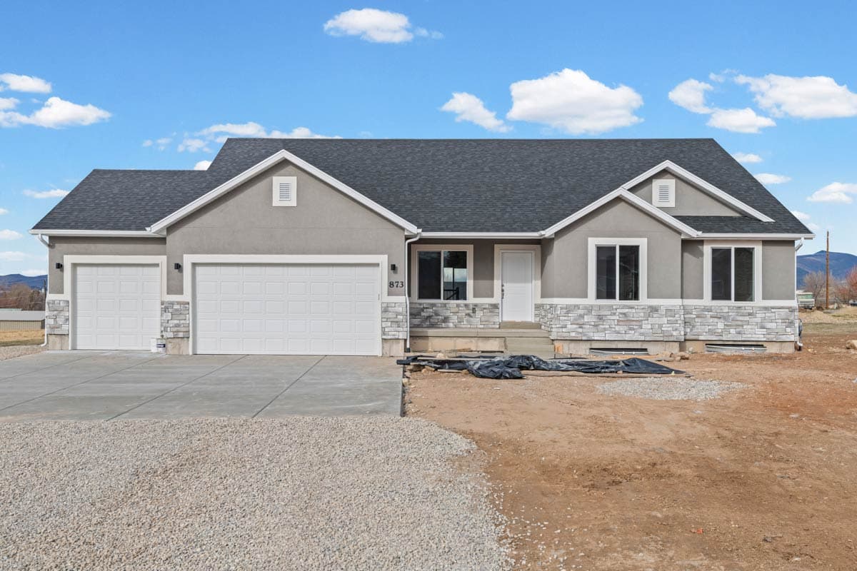 House plan exterior featuring a two-car garage, stone facade accents, multiple gables, and a front entry porch under a gray shingle roof.