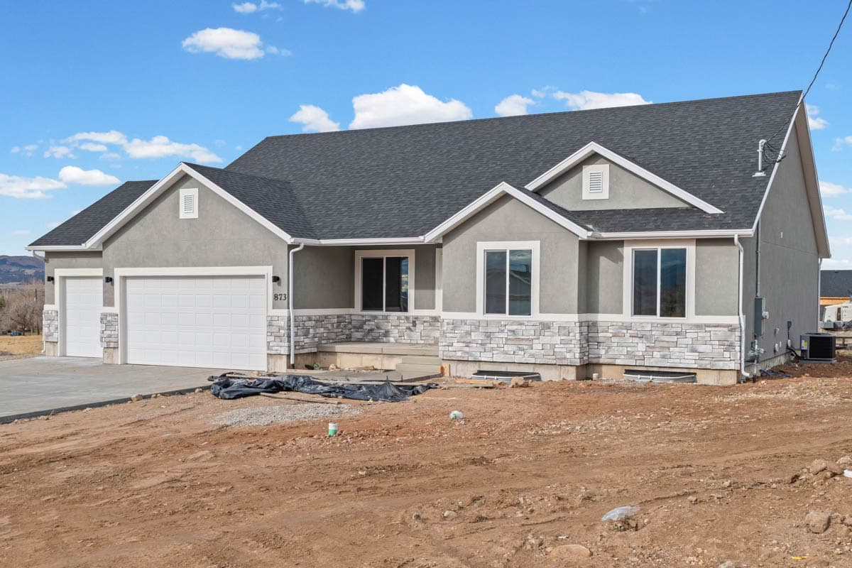 House plan exterior: One-story Modern Farmhouse with attached two-car garage, stone facade accents, and prominent gables.
